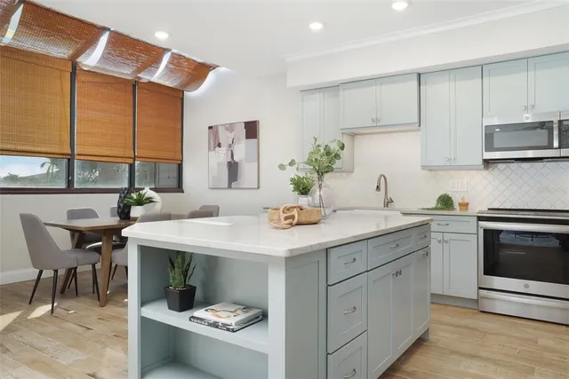 a kitchen with stainless steel appliances kitchen island granite countertop a table chairs sink and cabinets