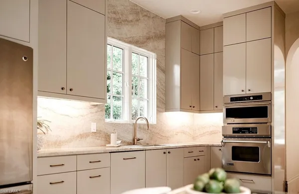 a kitchen with granite countertop a sink cabinets stainless steel appliances and a window