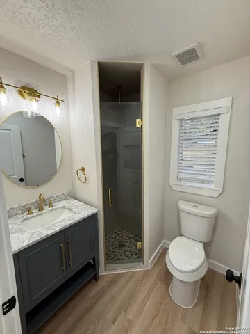 a bathroom with a granite countertop toilet a sink and a mirror