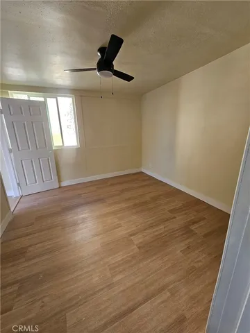 an empty room with wooden floor fan and windows