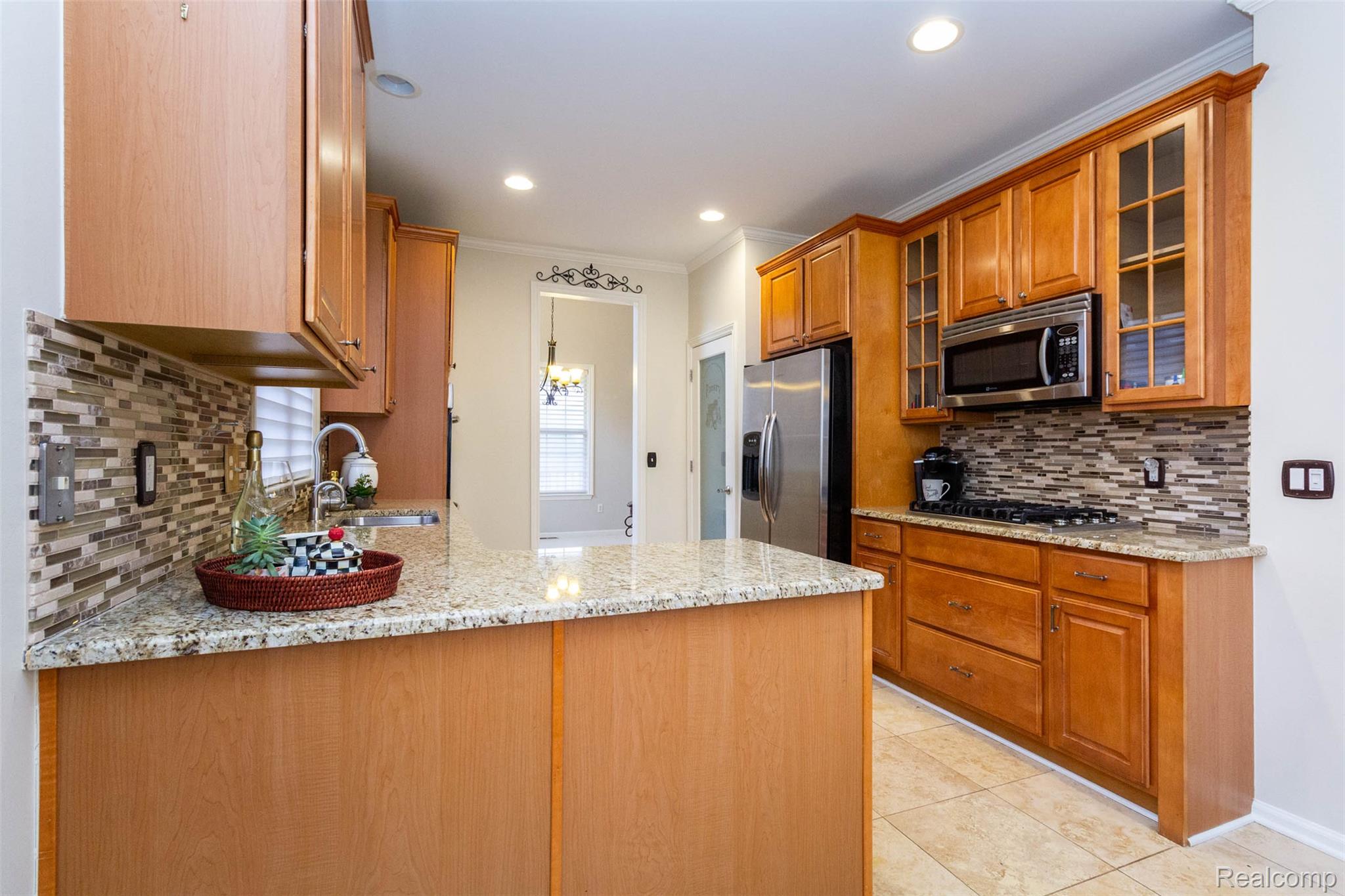 3805 Windingbrook Circle, Unit 22 Rochester, MI 48309 - Photo 29 of 63 Kitchen featuring wood finish cabinets, light stone counters, glass fronted cabinets, ornamental molding, and stainless steel appliances