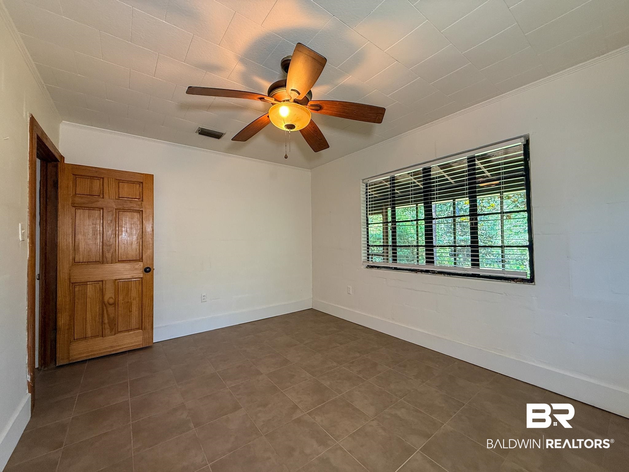 18711 Keller Road Foley, AL 36535 - Photo 25 of 38 Room featuring tile flooring, a window with horizontal blinds, a ceiling fan with integrated lighting, a paneled wooden door, and white baseboards