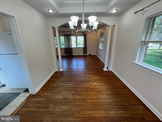 a view of a hallway with the wooden floor and chandelier