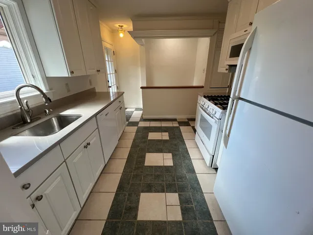 a hallway with white cabinets and black stainless steel appliances