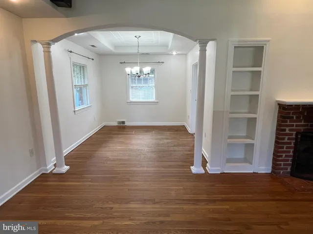 an empty room with wooden floor chandelier and entryway