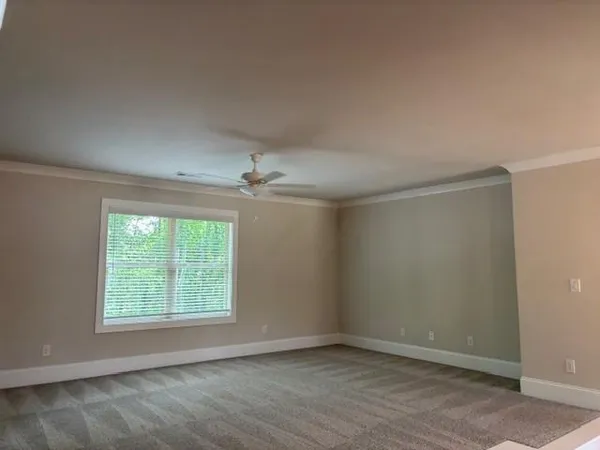 an empty room with a chandelier fan and windows