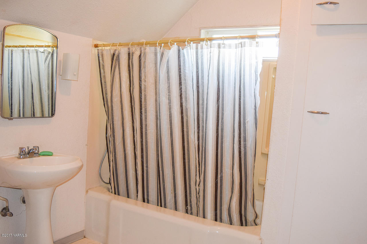 1001 Division Road Zillah, WA 98953 - Photo 18 of 24 a bathroom with a sink a mirror and a shower curtain
