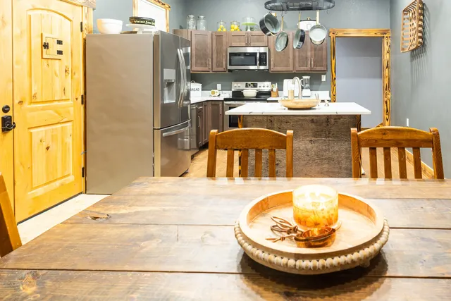 a room with stainless steel appliances kitchen island granite countertop a refrigerator a stove and a sink with living room view