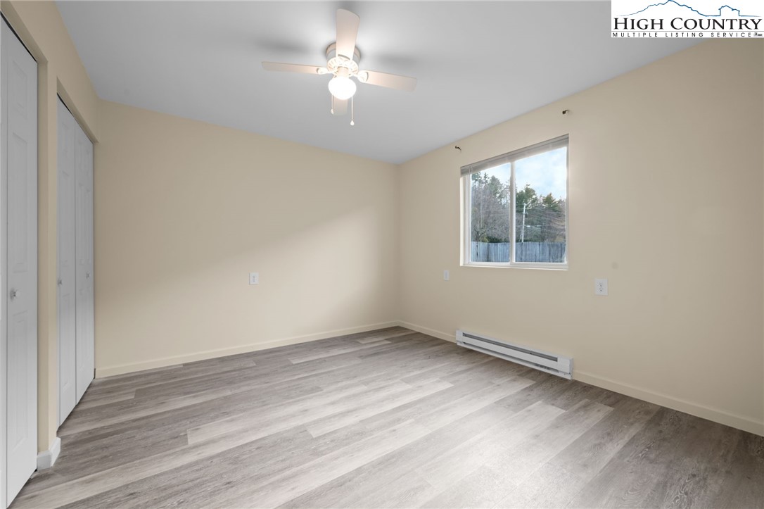 128 Zeb Street, Unit A101 Boone, NC 28607 - Photo 17 of 32 an empty room with wooden floor chandelier fan and windows