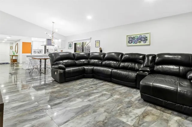 a living room with furniture and a view of kitchen