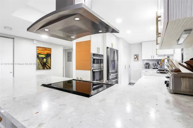 a kitchen with stainless steel appliances kitchen island granite countertop a refrigerator and a sink