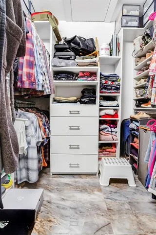a view of walk in closet with clothes and shoes