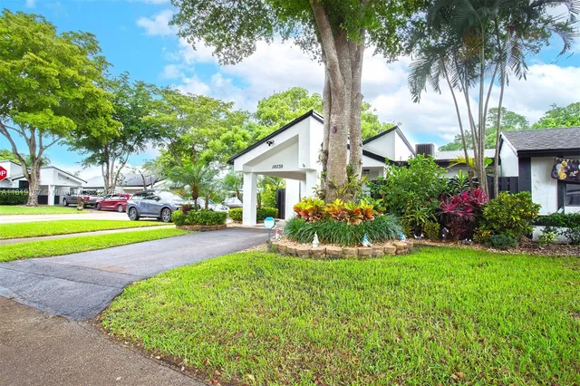 a view of a house with a swimming pool and a big yard with palm trees