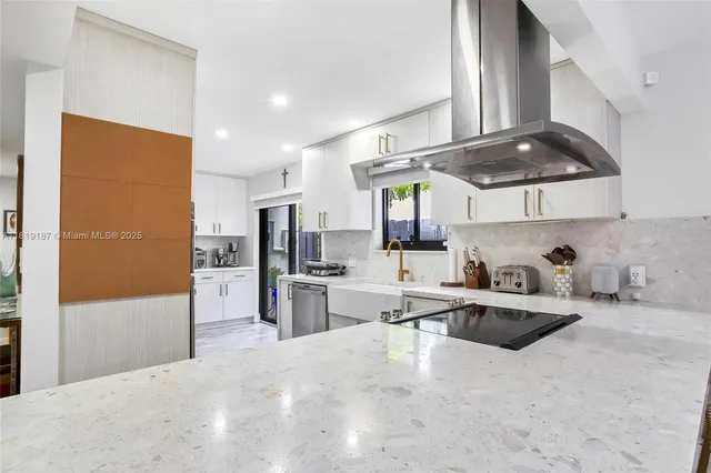 a kitchen with stainless steel appliances a sink a stove a refrigerator cabinets and a window