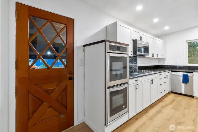 a kitchen with stainless steel appliances granite countertop white cabinets and window