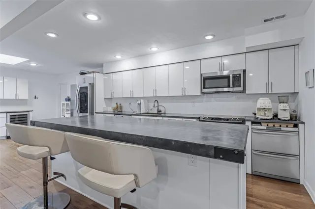 a large white kitchen with a sink and chairs