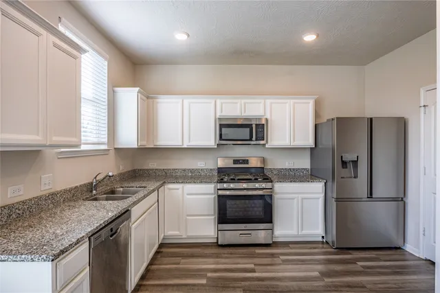 a kitchen with granite countertop a refrigerator stove and microwave