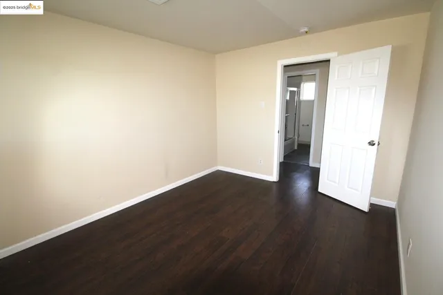a view of an empty room with wooden floor and closet