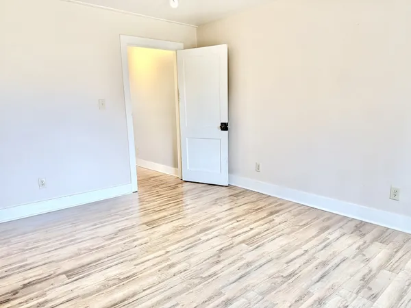 an empty room with wooden floor and entrance