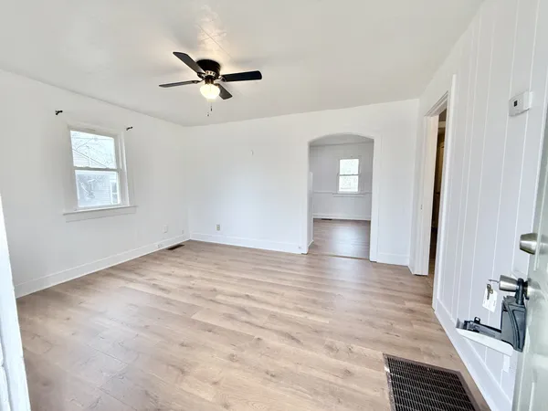 a view of empty room with wooden floor and fan