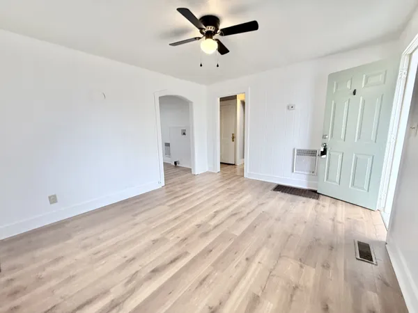 an empty room with wooden floor and ceiling fan