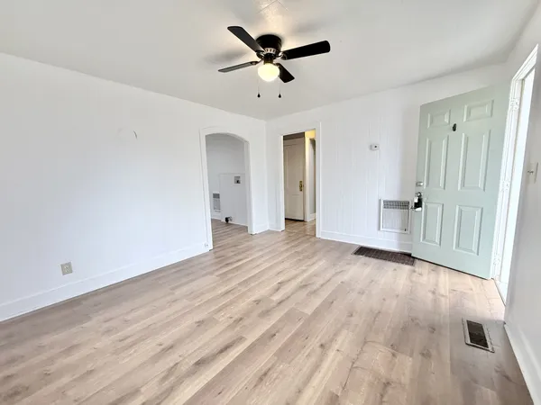 an empty room with wooden floor and ceiling fan