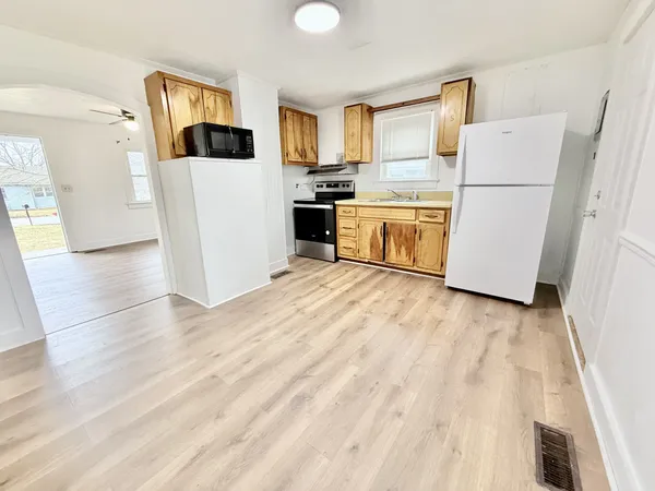 a kitchen with a refrigerator a stove top oven a counter space and wooden floor