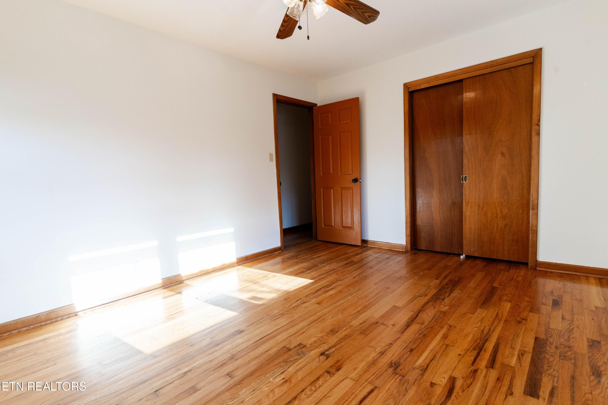 3424 Whittle Springs Road Knoxville, TN 37917 - Photo 8 of 29 a view of an empty room with wooden floor and a ceiling fan