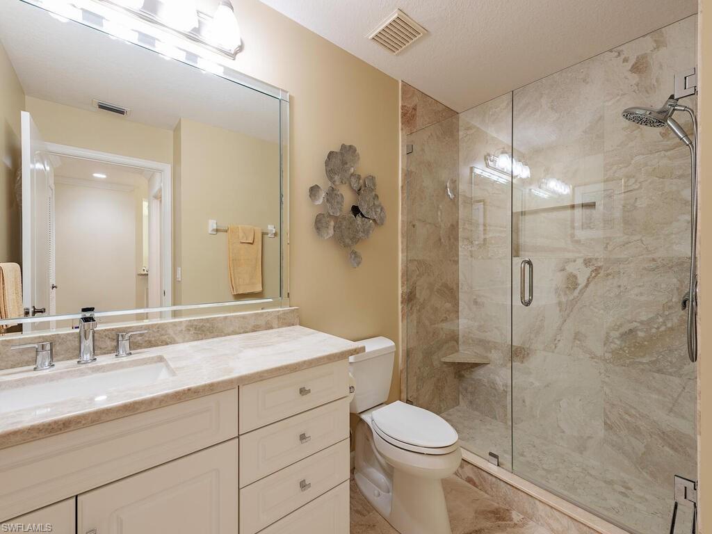 2433 Ravenna Boulevard, Unit 102 Naples, FL 34109 - Photo 9 of 12 Bathroom with visible vents, a shower stall, toilet, and vanity