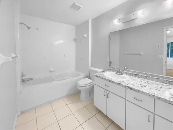 a bathroom with a granite countertop sink a toilet a mirror a bathtub and shower