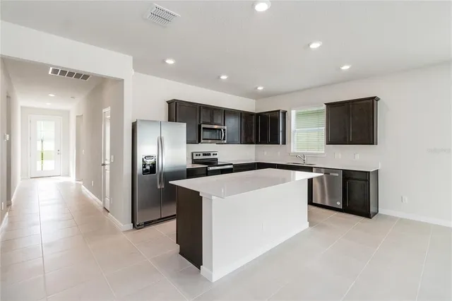 a large kitchen with a large counter top stainless steel appliances and cabinets