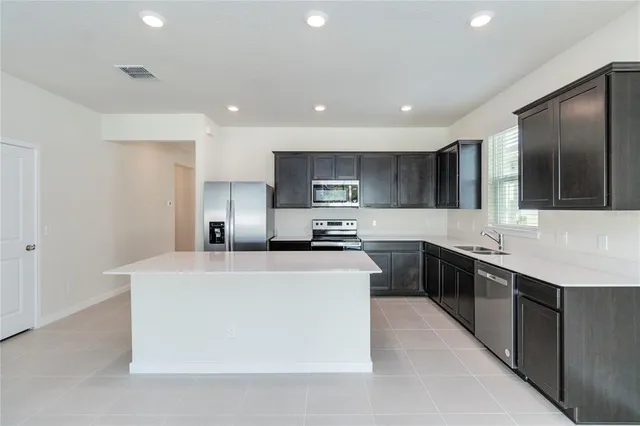 a large kitchen with stainless steel appliances a sink a stove a refrigerator and a oven with wooden floor