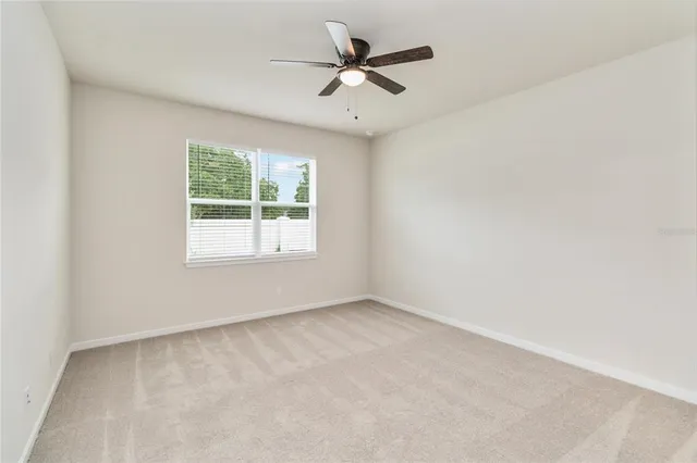 an empty room with a window and a fan