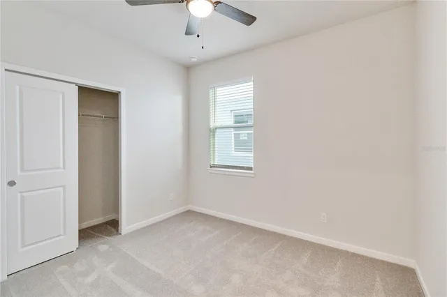 an empty room with a chandelier fan and windows