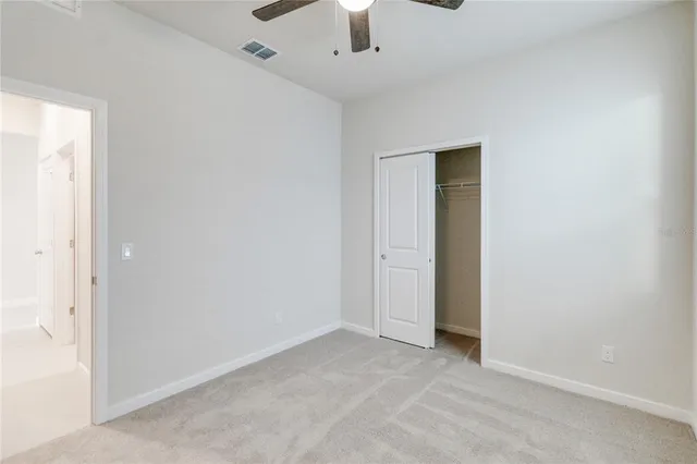 an empty room with a ceiling fan and carpet