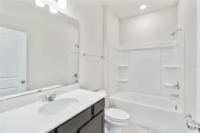 a bathroom with a bathtub shower sink vanity mirror and toilet
