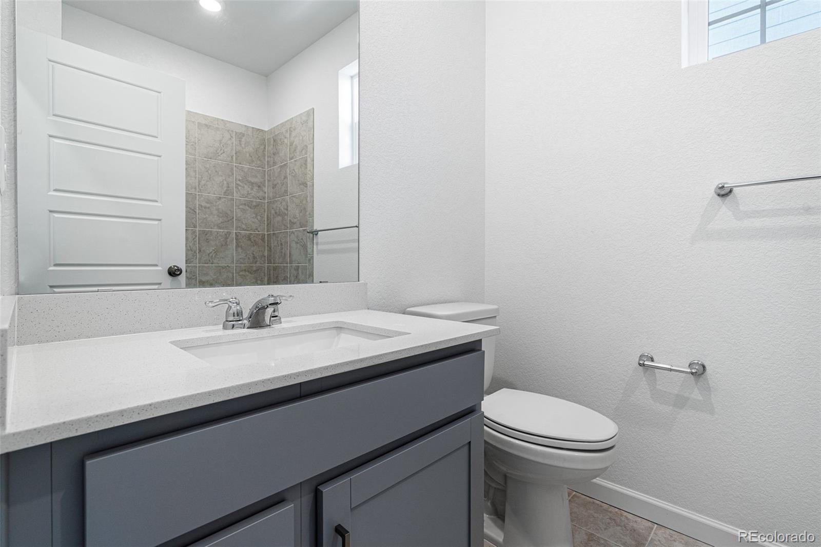 23936 River Front Drive Aurora, CO 80019 - Photo 19 of 46 a bathroom with a granite countertop sink a toilet and mirror