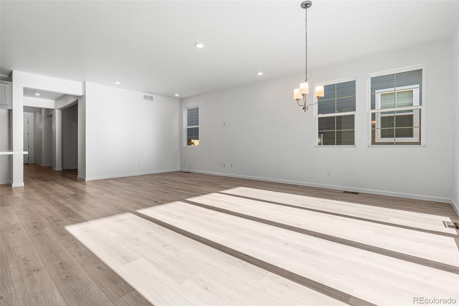 23936 River Front Drive Aurora, CO 80019 - Photo 6 of 46 a view of an empty room with wooden floor and kitchen view