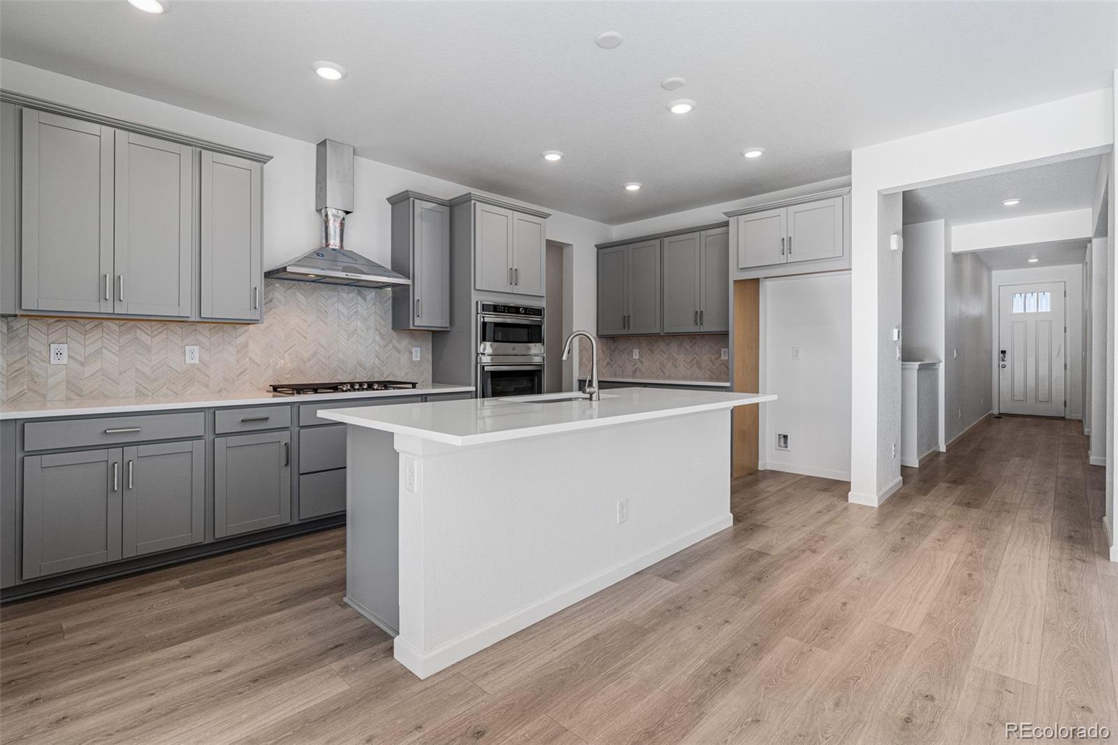 23936 River Front Drive Aurora, CO 80019 - Photo 10 of 46 a kitchen with kitchen island a sink a stove a refrigerator and white cabinets