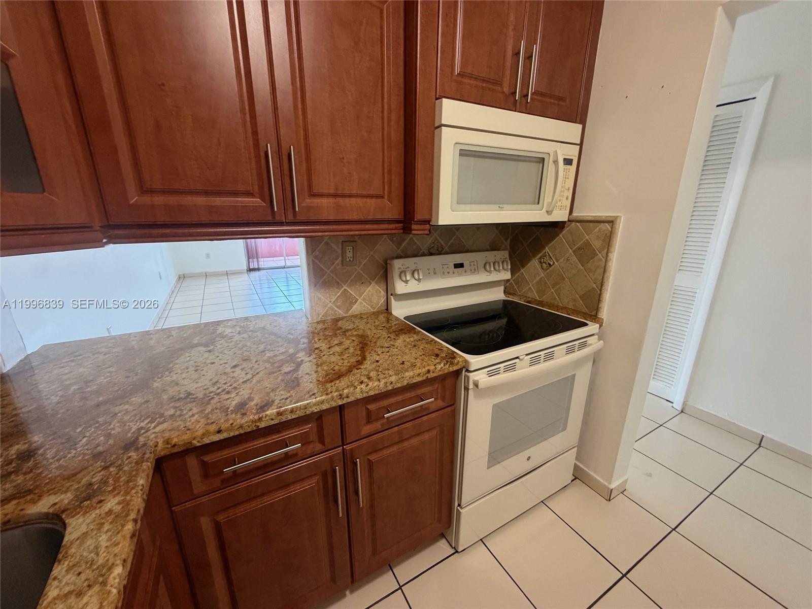 120 Royal Palm Road, Unit 301 Hialeah Gardens, FL 33016 - Photo 10 of 32 a kitchen with granite countertop white cabinets and white appliances