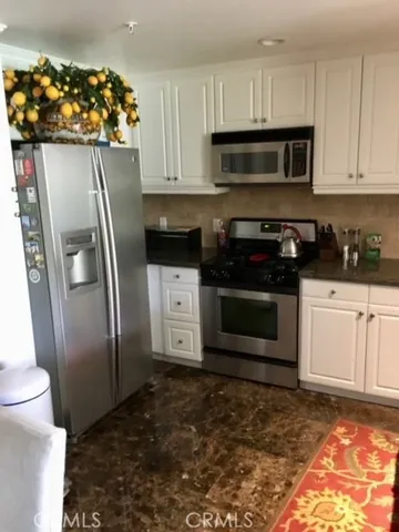 a kitchen with granite countertop a refrigerator stove and microwave