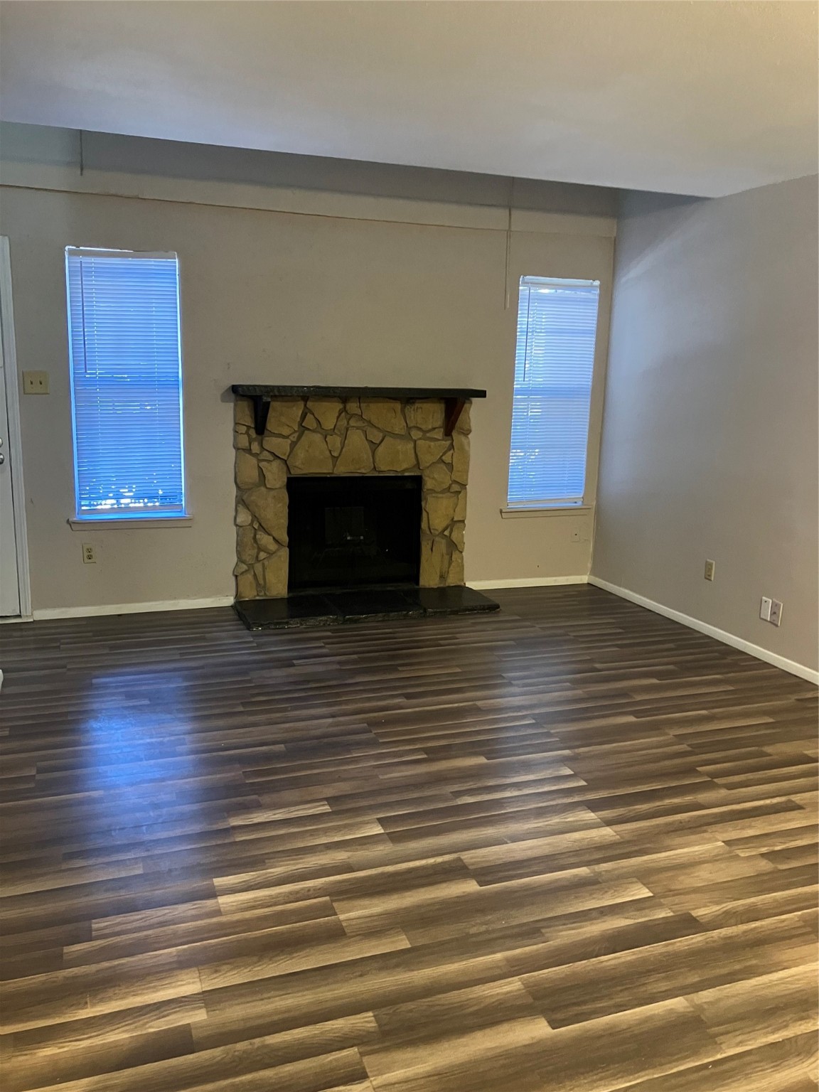 an empty room with wooden floor a fireplace and windows
