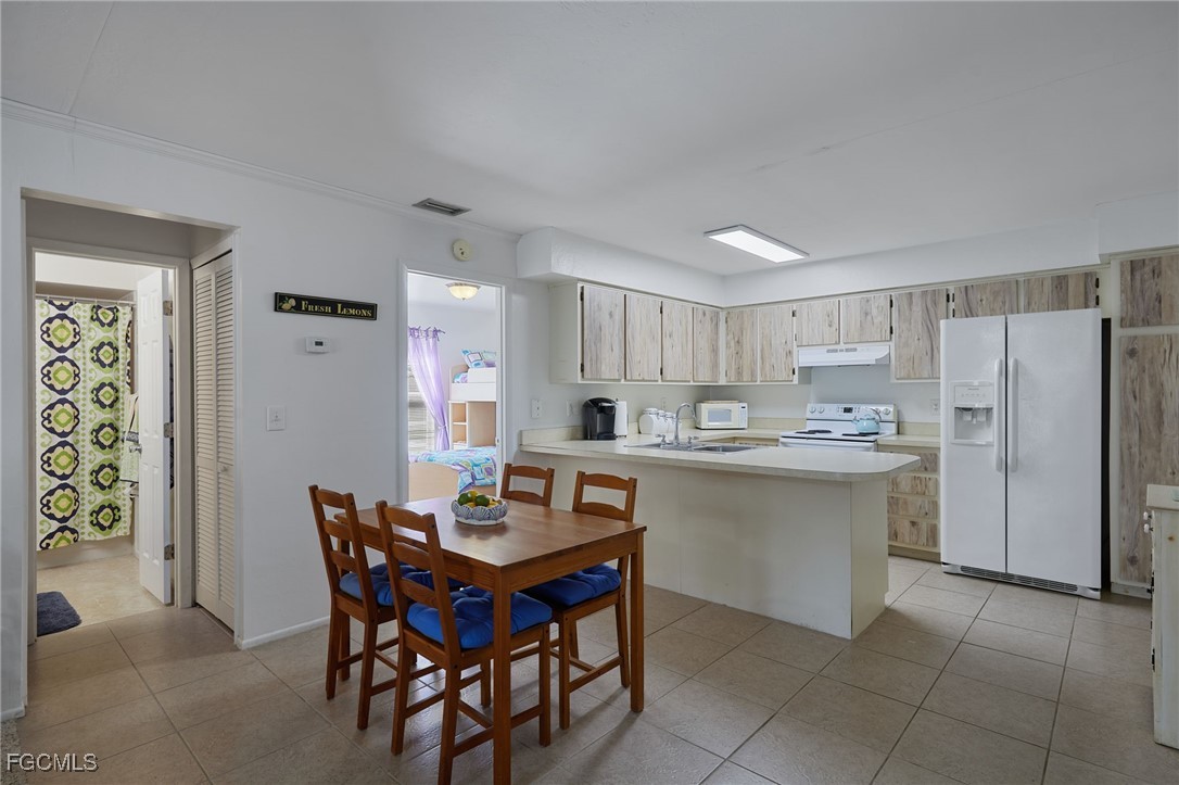 1100 Pondella Road, Unit 916 Cape Coral, FL 33909 - Photo 8 of 26 a kitchen with a dining table chairs refrigerator and cabinets