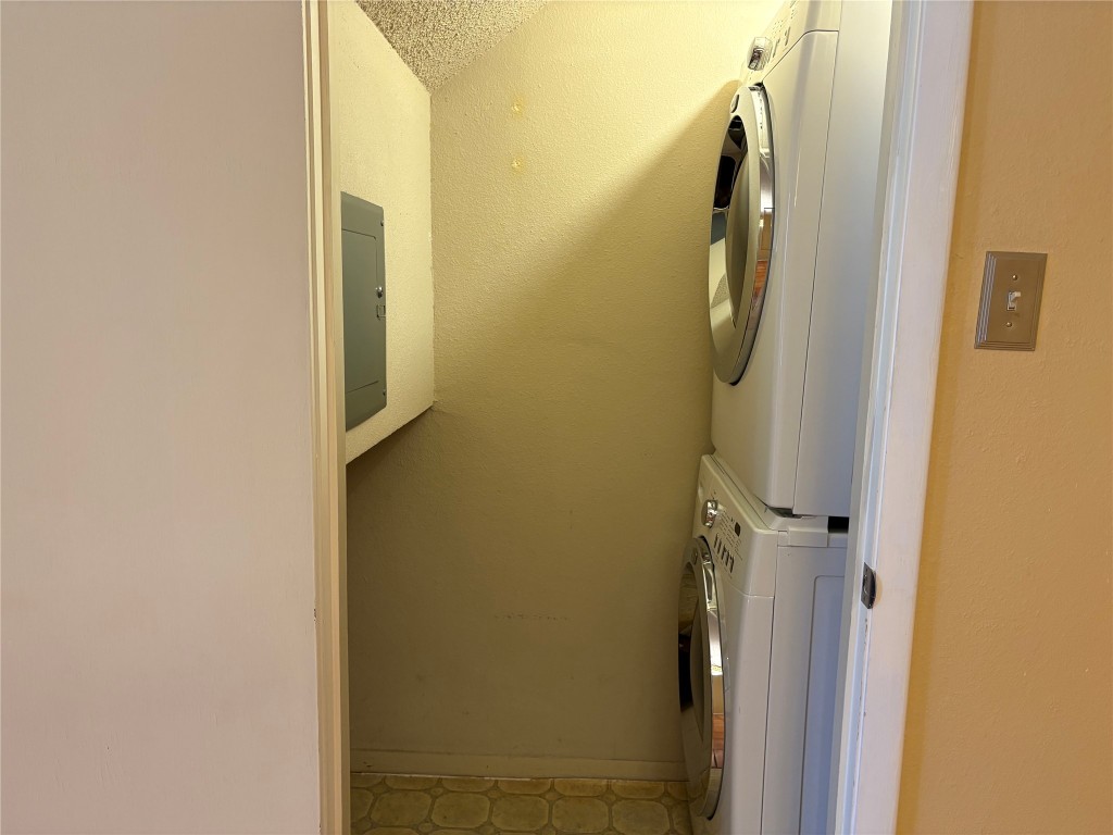 9226 Jollyville Road, Unit 144 Austin, TX 78759 - Photo 13 of 40 Laundry area with stacked washing machine and dryer, electric panel, and storage under the stairs
