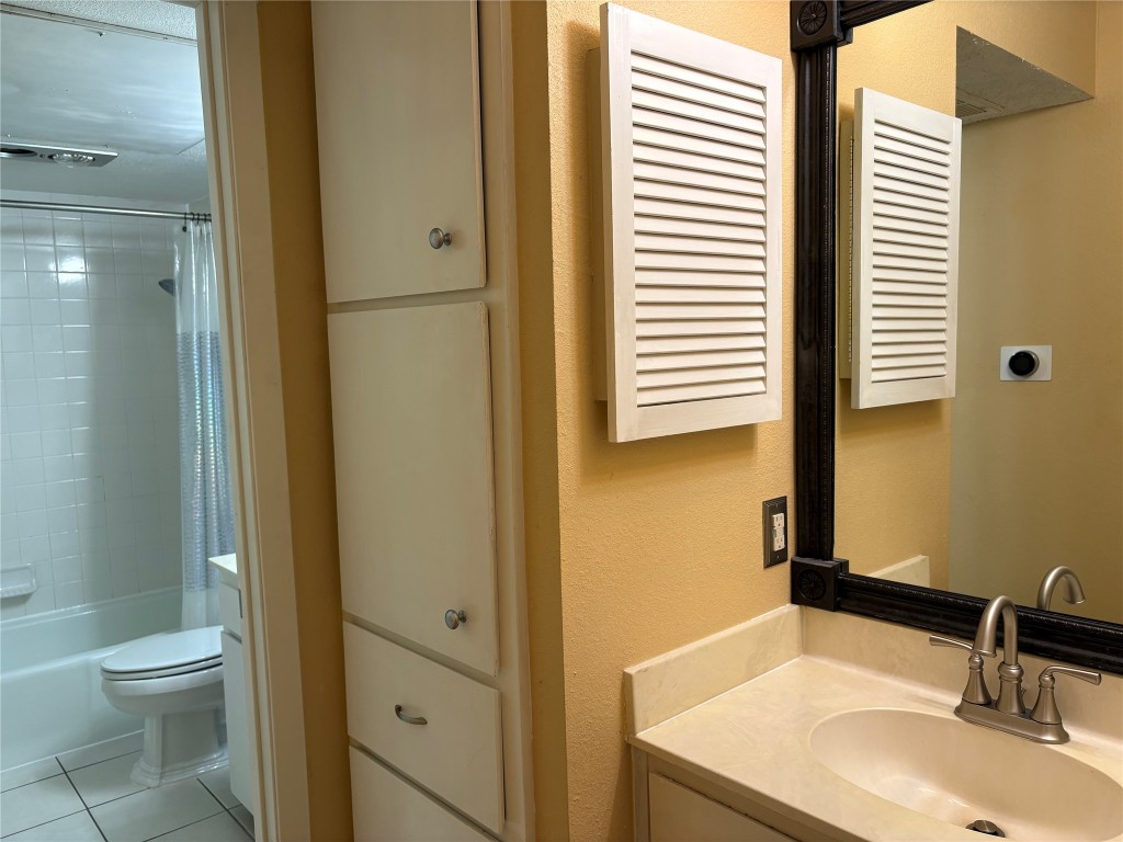9226 Jollyville Road, Unit 144 Austin, TX 78759 - Photo 23 of 40 Full bathroom with vanity, shower / bathtub combination with curtain, light tile floors, and a textured wall