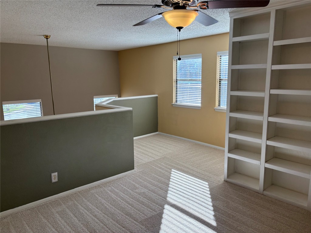9226 Jollyville Road, Unit 144 Austin, TX 78759 - Photo 25 of 40 Unfurnished room featuring a ceiling fan, light carpet, and a textured ceiling with lots of cabinet space