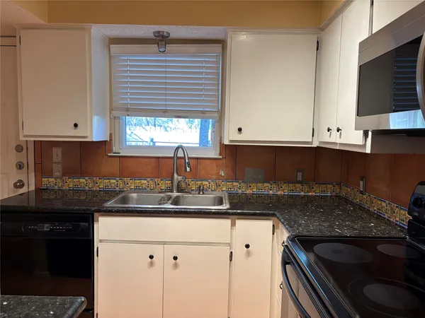 a kitchen with granite countertop a sink stove and cabinets