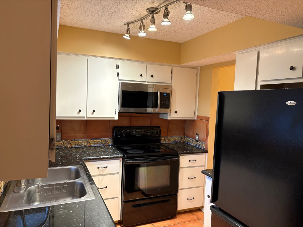 9226 Jollyville Road, Unit 144 Austin, TX 78759 - Photo 8 of 40 Kitchen with black appliances, a textured ceiling, light tile patterned floors, white cabinets, and dark stone countertops