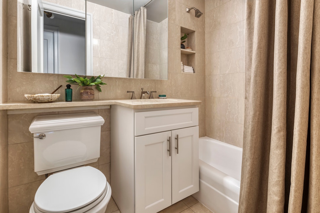155 West 68th Street, Unit 1702 Manhattan, NY 10023 - Photo 8 of 17 a bathroom with a toilet sink vanity and mirror