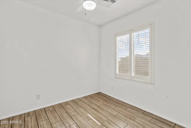 a view of an empty room with window and wooden floor